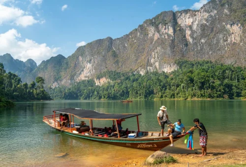 Traditional longtail boat at Cheow Lan Lake surrounded by limestone cliffs in Khao Sok National Park, Thailand