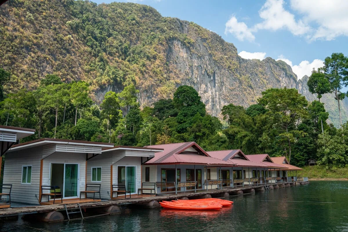 Floating bungalows on Cheow Lan Lake surrounded by lush rainforest and towering limestone mountains in Khao Sok, Thailand