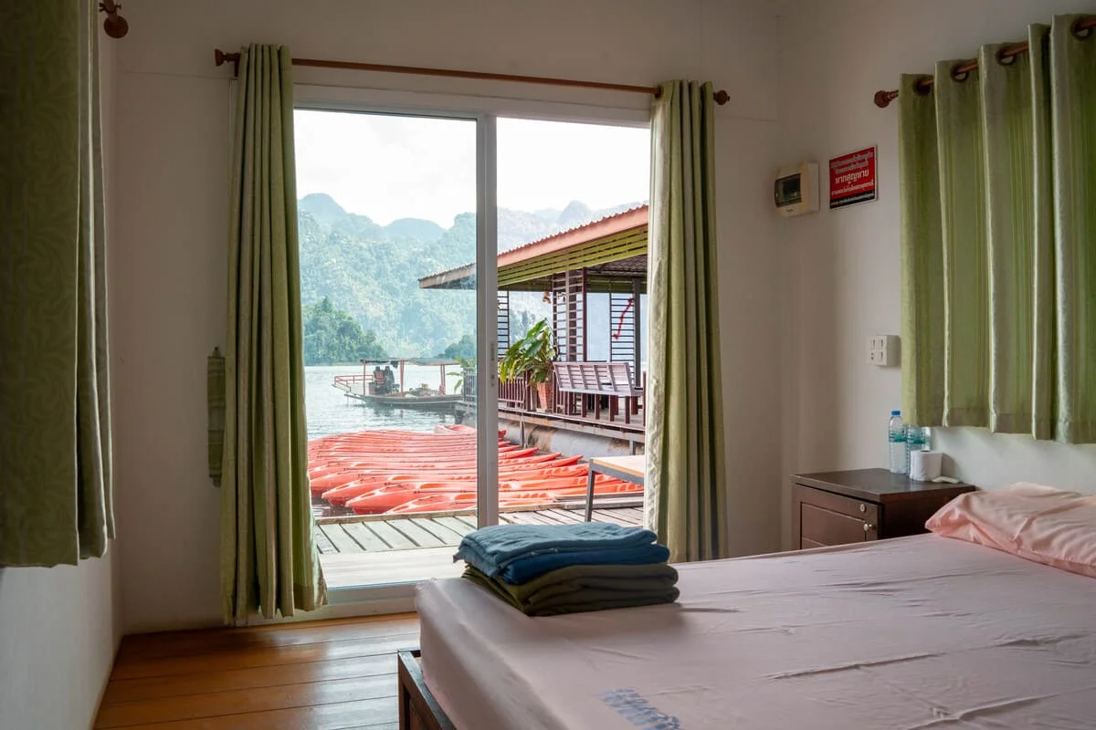 View of Cheow Lan Lake and orange kayaks from the bedroom of a floating bungalow in Khao Sok National Park