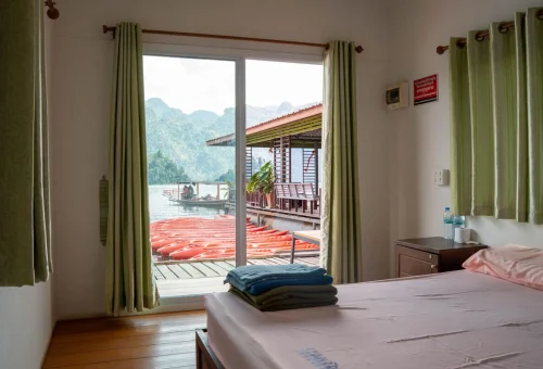 View of Cheow Lan Lake and orange kayaks from the bedroom of a floating bungalow in Khao Sok National Park