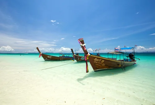 Longtail boats silhouetted against a pastel colors over Phi Phi Islands’ calm waters