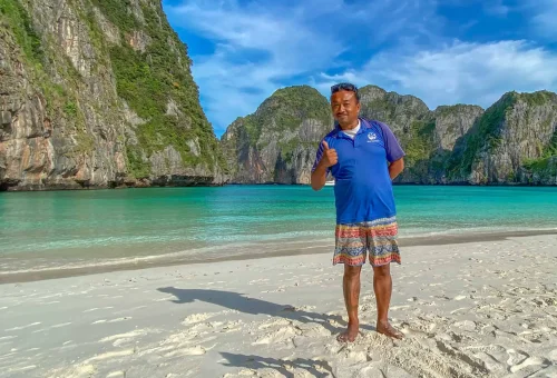 Guest standing alone on the pristine beach of Maya Bay at sunrise, surrounded by limestone cliffs and calm turquoise waters — part of the Phi Phi Islands X-Large Early Bird tour.