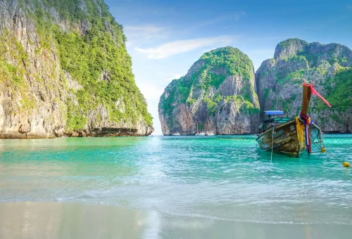 Early morning view of Maya Bay on the Phi Phi Islands — empty beach, soft sunrise light, turquoise water, and dramatic limestone cliffs, part of the X-Large Early Bird tour.