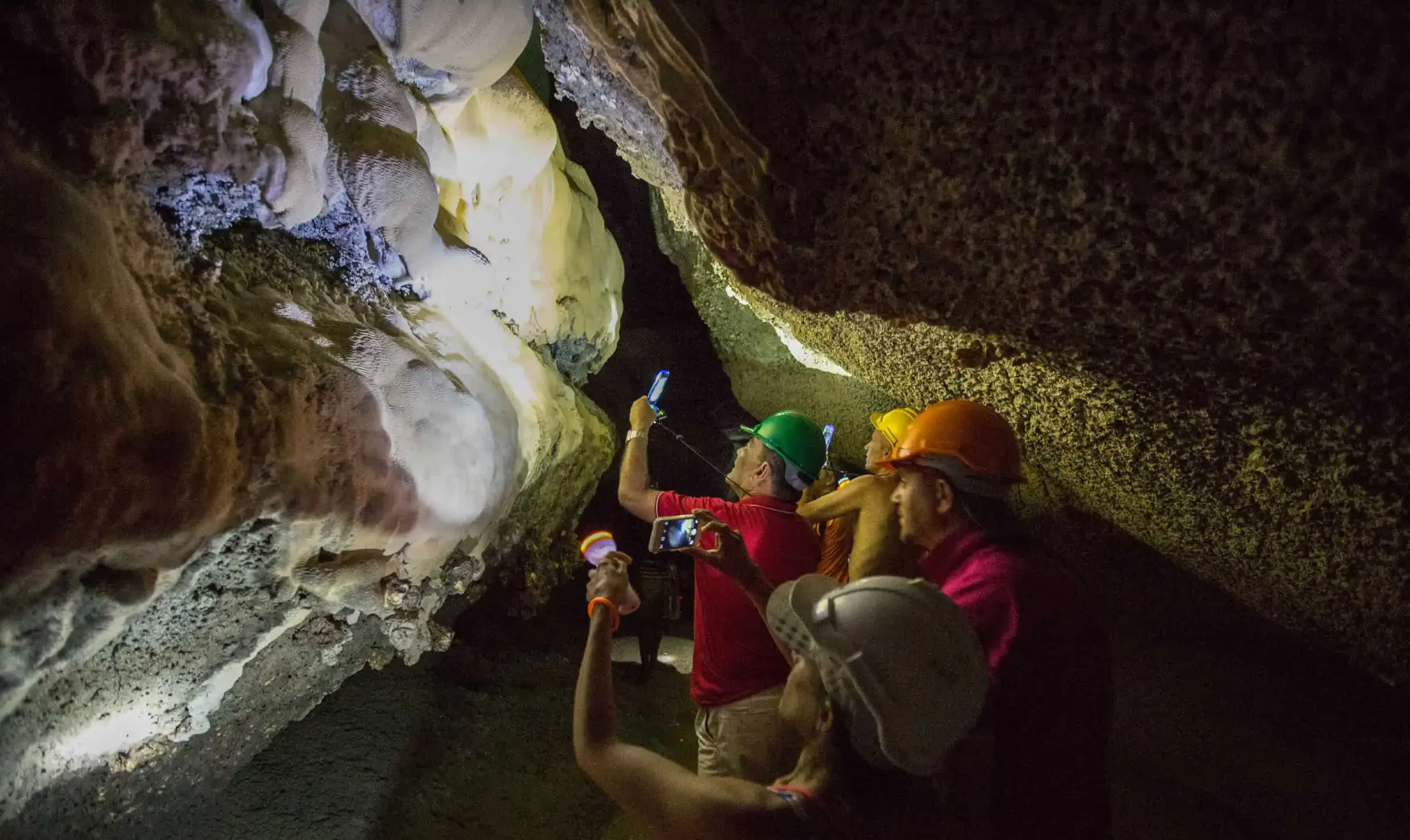 Adventurers hiking through a dramatic limestone cave with sunlight filtering through the entrance, during the early departure James Bond Island Tour.
