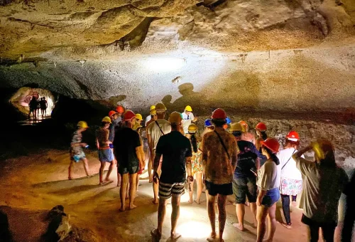 Guests exploring a sea cave during the early departure James Bond Island Tour — dramatic rock formations, low ceilings, and reflections on the water.