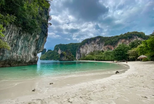 Peaceful beach at Hong Island with soft white sand, clear turquoise water, and limestone cliffs in the background, part of the Krabi 4 Islands Tour.