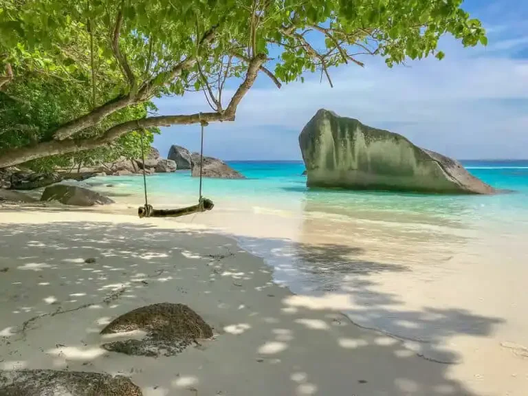 Tranquil Honeymoon Bay at Similan Island with white sand, calm turquoise water, and lush green hills in the background