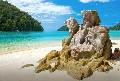 Unique rock formation known as the symbol of Surin Island, rising from the turquoise sea with lush greenery in the background