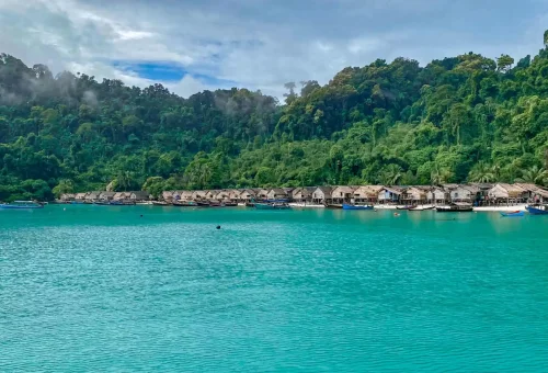 Traditional Sea Gypsy (Moken) Village at Surin Island with wooden stilt houses along the shore and boats anchored nearby