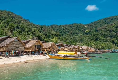 Moken sea nomads at Surin Island engaging in daily life near their stilt houses by the sea, with boats and natural surroundings