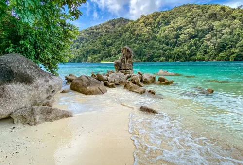 Tropical beach on Surin Island with white sand, turquoise water, and lush palm trees under a sunny blue sky