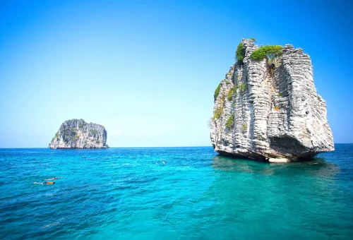 Majestic limestone formations rising from the turquoise waters at Koh Haa, surrounded by coral reefs and clear skies