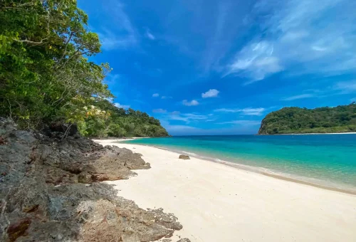 Pristine white sand and turquoise water at Koh Rok's magic beach with lush greenery and peaceful tropical scenery