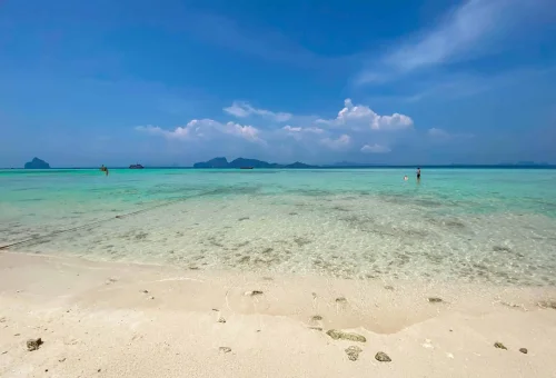 Wide stretch of white sandy beach at Koh Kradan with clear turquoise water and a vast, open tropical landscape