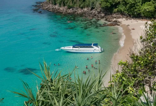 Speedboat anchored on the shore of Koh Kradan with crystal-clear water, white sand, and tropical scenery in the background