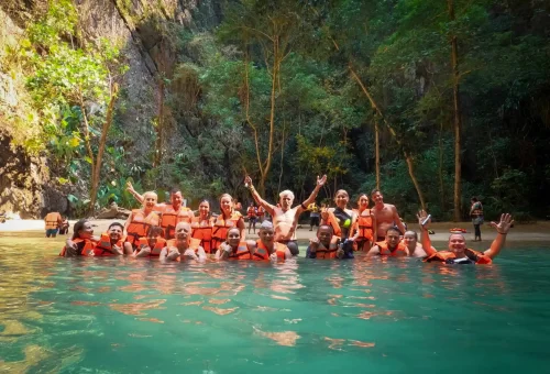 Entrance to the Emerald Cave at Koh Mook with kayakers paddling through a narrow tunnel surrounded by limestone cliffs