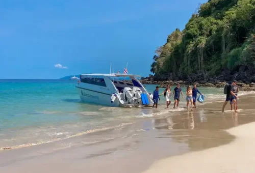 Visitors arriving by boat at Koh Kradan’s sunset beach, greeted by calm waters, golden light, and a serene tropical setting