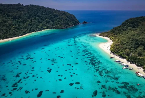 Aerial view of Koh Rok with turquoise waters, coral reefs, and white sandy beaches surrounded by lush greenery