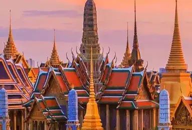 Ornate Bangkok temple with golden spires, intricate details, and traditional Thai architecture under a clear sky