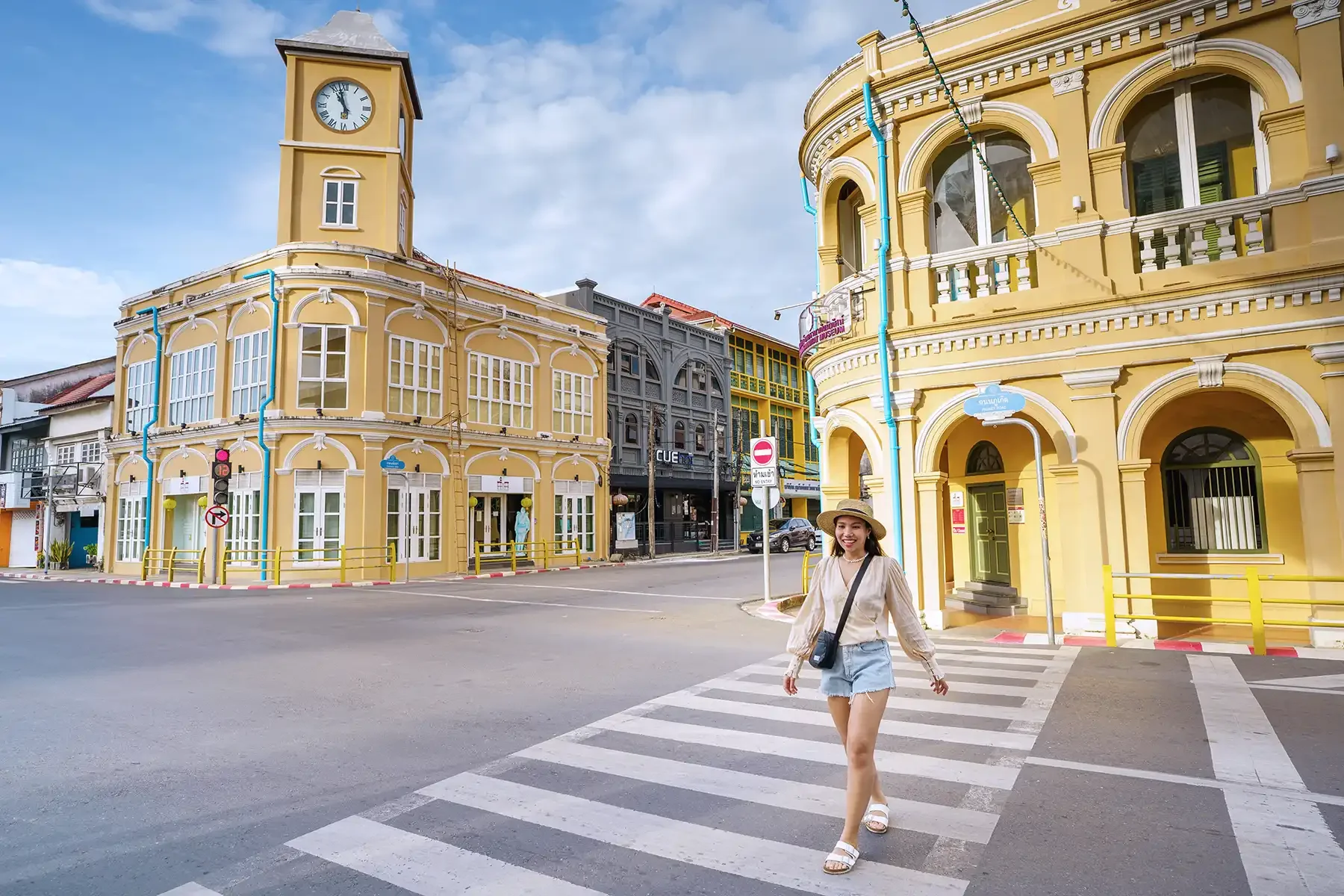 Iconic yellow clock tower in Phuket Old Town, showcasing colonial-style architecture against a clear blue sky