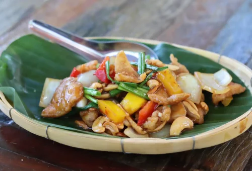 Traditional Thai chicken with cashew nuts dish served at Old Phuket Farm on a rustic wooden table