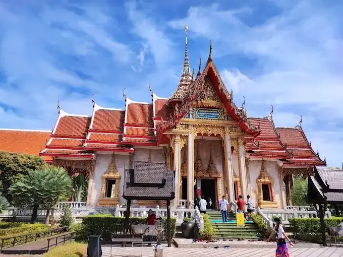 Travelers visiting a serene Buddhist temple in Phuket, surrounded by traditional architecture and lush greenery
