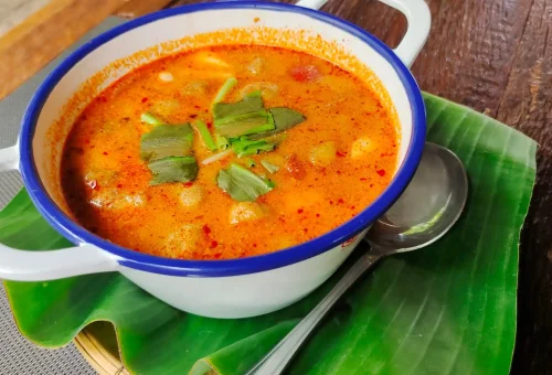 Visitors enjoying a Thai cooking class at Old Phuket Farm, gathered around a traditional outdoor cooking station