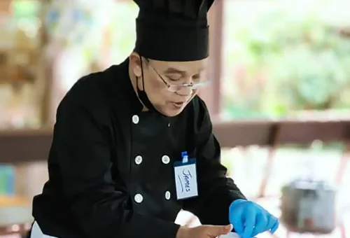 Close-up of a Thai dish being cooked during a class at Old Phuket Farm, featuring fresh herbs and traditional ingredients