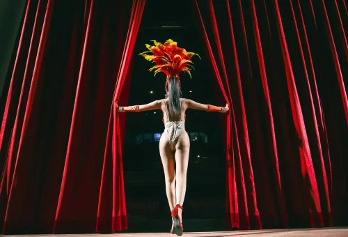 Simon Cabaret Phuket performers in synchronized dance formation wearing coordinated, sparkling costumes on a colorful stage.