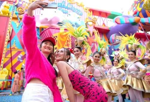 Fantasy-style bridge illuminated with colorful lights over water at night in Carnival Magic Phuket
