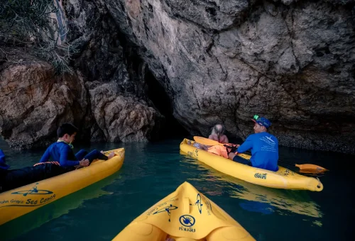 Canoe gliding through a glowing sea cave at sunset during the Hong Island by Starlight tour