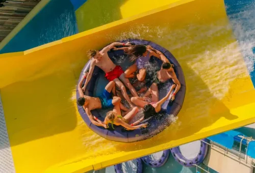 Excited guests racing down vibrant, twisting water slides at Andamanda Phuket Waterpark with splashes and smiles all around.