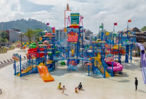 Young children enjoying safe and colorful kiddie water slides at Andamanda Phuket Waterpark, with lifeguards nearby and playful water features.