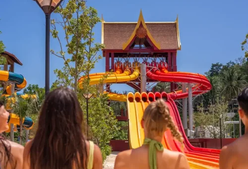 Visitors speeding down towering, twisty water slides at Andamanda Phuket Waterpark, with big splashes and excited expressions.