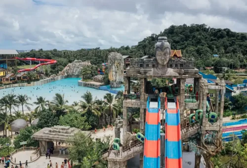 A massive, winding water slide at Andamanda Phuket Waterpark with riders zooming down in inflatable rafts, surrounded by tropical scenery.