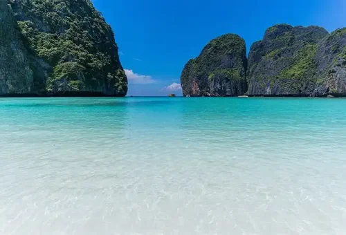 Stunning view of Maya Bay with turquoise water, white sand, and towering limestone cliffs, seen from a speed catamaran at Phi Phi Islands.