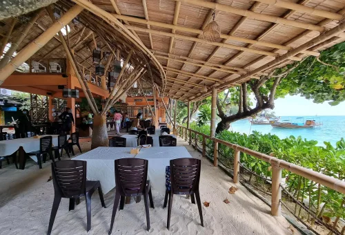 Guests serving themselves from a tropical-style lunch buffet with Thai cuisine at a shaded outdoor area near the beach on Phi Phi Islands.