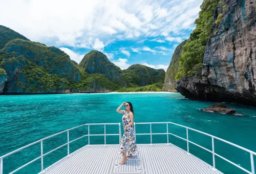 Scenic view of Maya Bay's turquoise waters and dramatic cliffs, captured from the deck of a speed catamaran approaching the Phi Phi Islands.