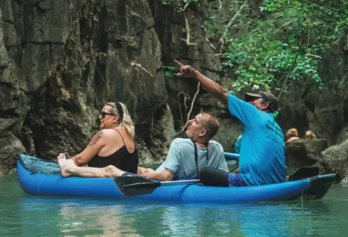 Canoeing through serene waters with Andaman Sea Kayak, surrounded by towering limestone cliffs and lush greenery under a clear sky.