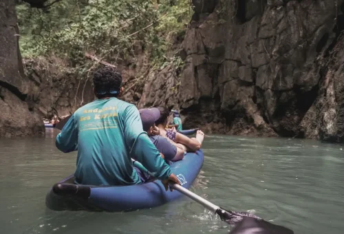 Experienced paddle guides leading a canoe through a limestone cave with Andaman Sea Kayak, navigating calm waters beneath dramatic rock formations.