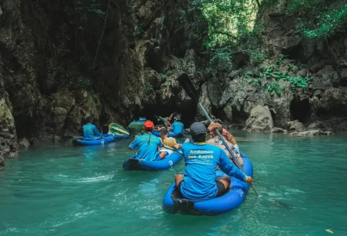 A canoe gliding through a narrow limestone cave during the Andaman Sea Kayak tour, with shimmering water and natural rock formations overhead.