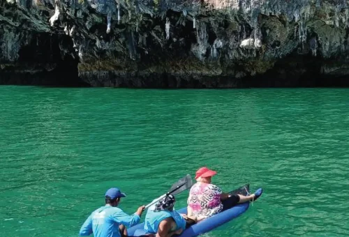 A canoe peacefully floating through a serene lagoon surrounded by limestone cliffs and lush greenery during the Andaman Sea Kayak tour.