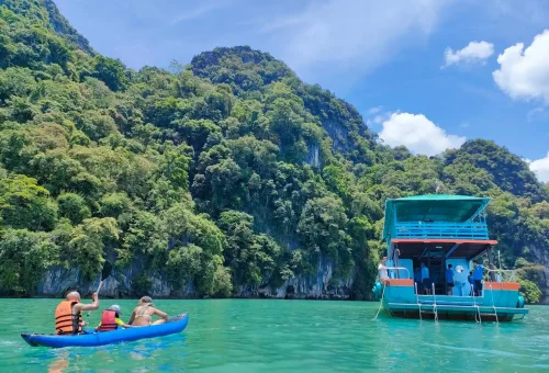 Guests returning to the main boat after kayaking, preparing to enjoy a Thai lunch buffet onboard with Andaman Sea Kayak, surrounded by scenic sea views.