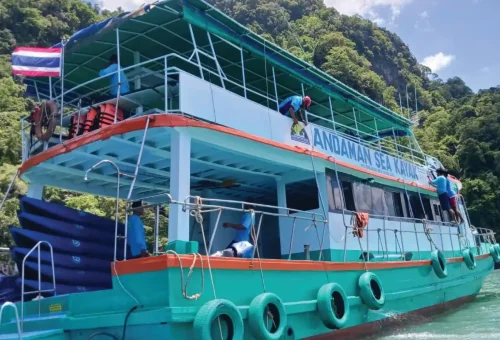 The main Andaman Sea Kayak boat anchored in calm waters, equipped with canoes and supplies, ready for guests to begin their sea cave adventure.