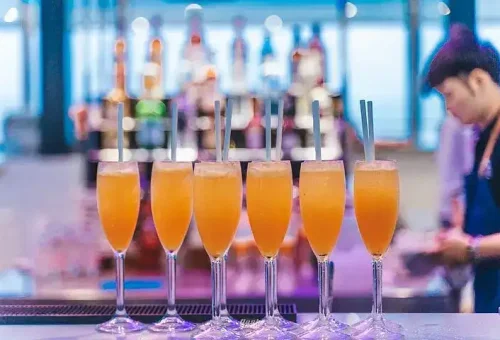 Guests enjoying colorful cocktails on the deck of a luxury catamaran near James Bond Island, with scenic ocean views and a relaxed atmosphere.