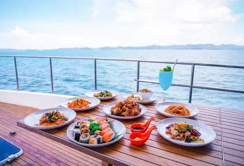 Beautifully arranged lunch setup on a luxury catamaran near James Bond Island, featuring Thai dishes, fresh fruit, and ocean views in the background.