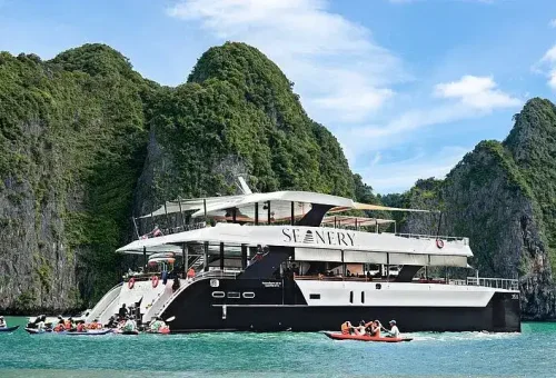 Wide-angle view from a luxury catamaran showing stylish deck seating, open sea, and surrounding limestone islands near James Bond Island.