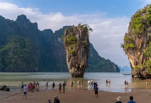 A serene view of James Bond Island (Koh Tapu) with no crowds, captured from a luxury catamaran anchored nearby in calm, turquoise waters.