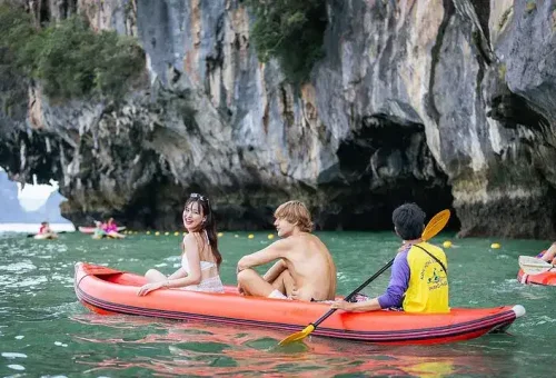 A guided canoe tour at Hong Island during the Phang Nga Bay Party Cruise, with guests paddling through calm waters surrounded by limestone cliffs.