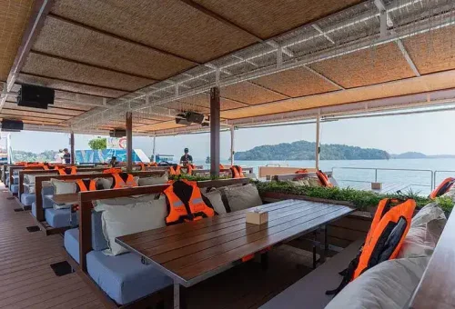 A cozy and stylish seating area on the deck of the Phang Nga Bay party boat, featuring plush cushions and open-air ocean views.